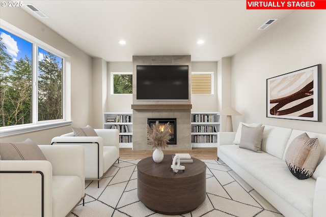 living room featuring light wood-type flooring and a tiled fireplace