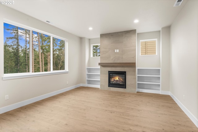 unfurnished living room featuring a tile fireplace, hardwood / wood-style floors, and built in features