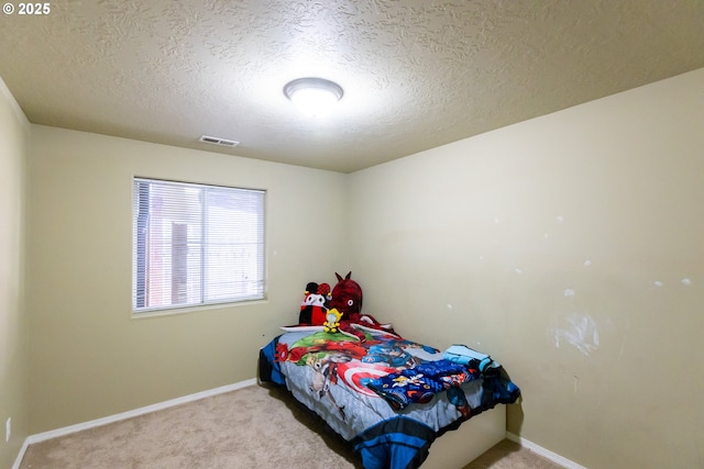 bedroom with carpet floors, visible vents, a textured ceiling, and baseboards