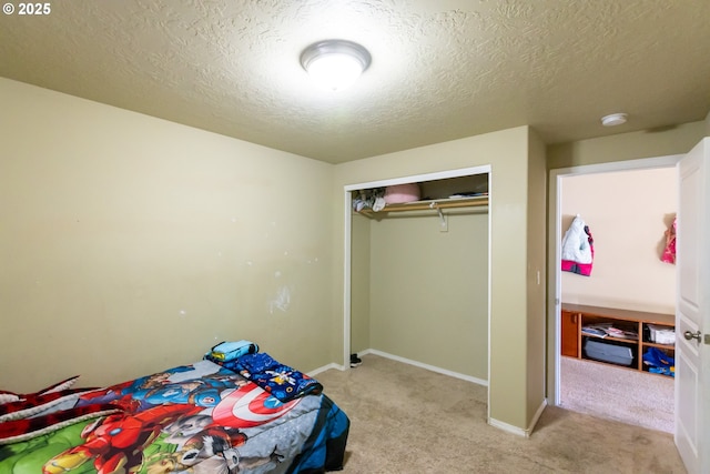 carpeted bedroom featuring a textured ceiling, a closet, and baseboards