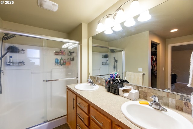 full bath with tasteful backsplash, a stall shower, and a sink