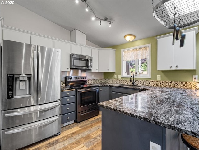 1908 NW 4th Ave, Battle Ground, WA 98604 - kitchen featuring stainless steel appliances, vaulted ceiling, a sink, white cabinets, and light wood-style flooring
