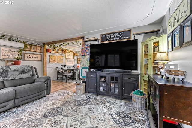 living room featuring wood-type flooring, a wall mounted air conditioner, and a textured ceiling