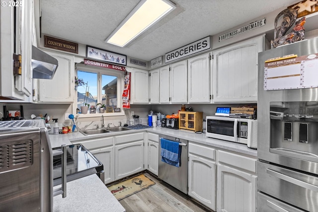 kitchen with white cabinetry, sink, wall chimney range hood, and stainless steel appliances