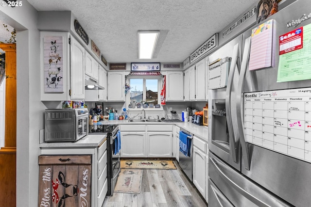 kitchen with sink, white cabinets, stainless steel appliances, a textured ceiling, and light wood-type flooring