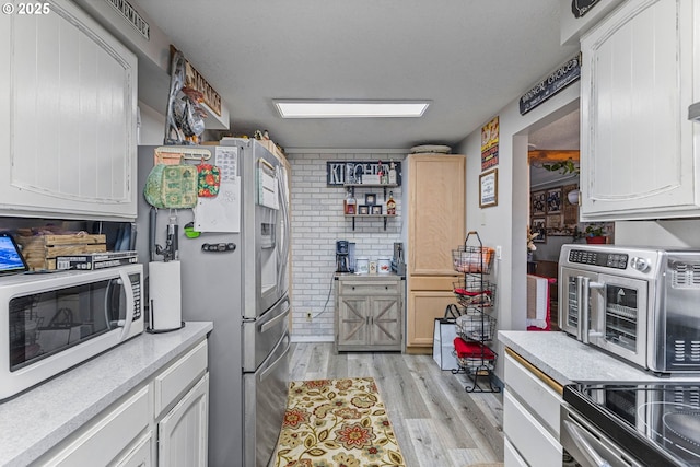 kitchen with white cabinetry, stainless steel refrigerator with ice dispenser, and light wood-type flooring