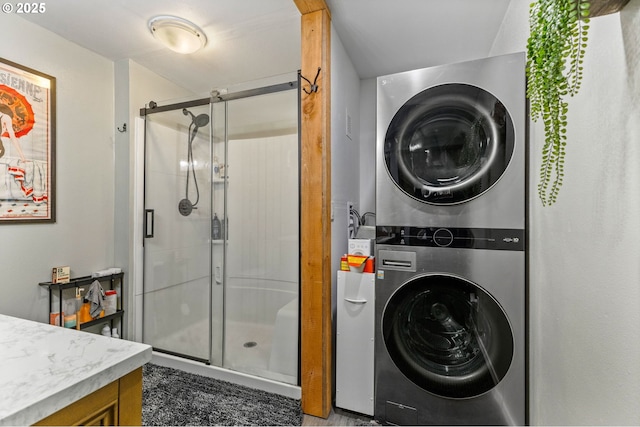 bathroom with vanity, stacked washing maching and dryer, and a shower with door