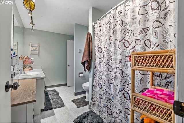 bathroom with vanity, track lighting, and toilet