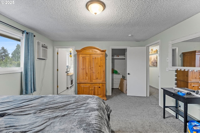 bedroom with a wall mounted air conditioner, light carpet, and a textured ceiling