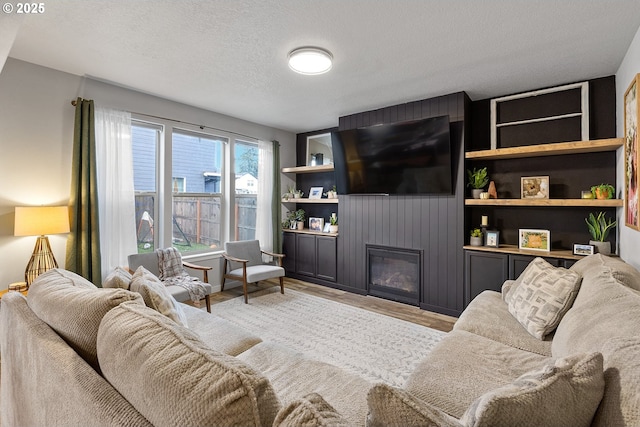 living room featuring a textured ceiling, light hardwood / wood-style floors, built in features, and a fireplace