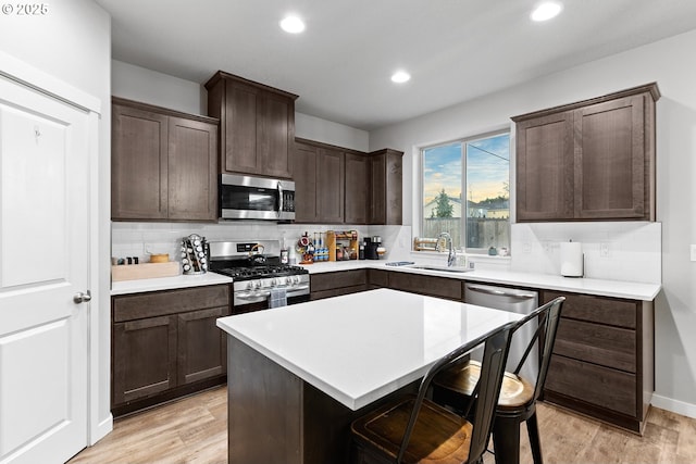 kitchen featuring light hardwood / wood-style floors, sink, appliances with stainless steel finishes, and a breakfast bar area