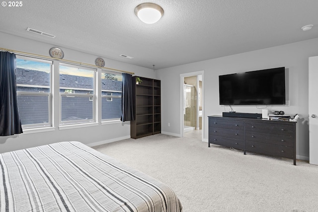 carpeted bedroom featuring a textured ceiling and ensuite bath