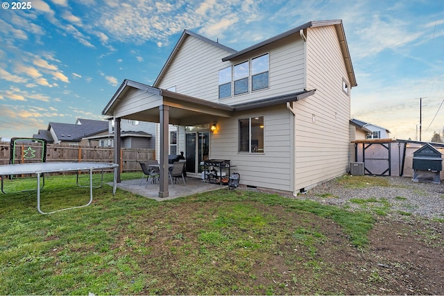 back of house with a yard, a trampoline, cooling unit, a shed, and a patio