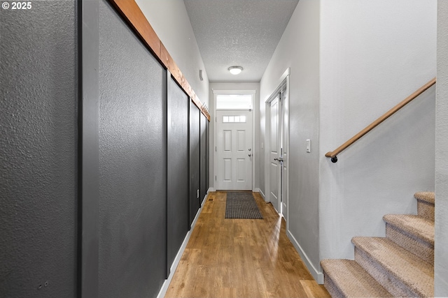 doorway to outside with light hardwood / wood-style flooring and a textured ceiling