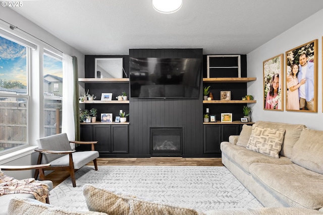 living room with built in features, a large fireplace, and light hardwood / wood-style flooring