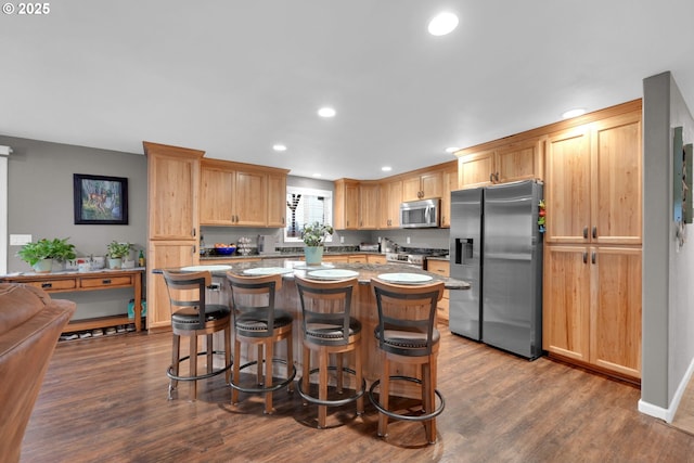 kitchen with a kitchen island, a breakfast bar area, dark wood-type flooring, stainless steel appliances, and recessed lighting