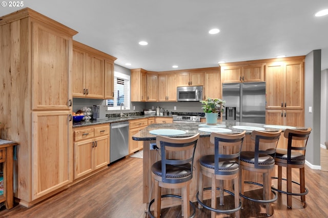 kitchen featuring a kitchen bar, appliances with stainless steel finishes, dark wood-style flooring, and a center island