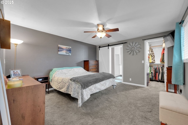 bedroom featuring a barn door, carpet flooring, baseboards, a spacious closet, and a closet