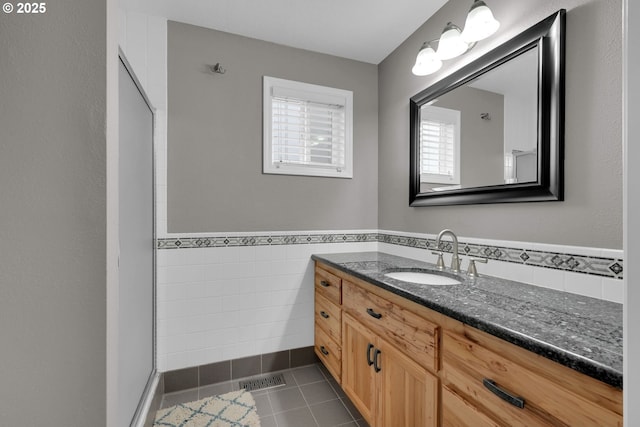 bathroom with a wainscoted wall, visible vents, tile walls, vanity, and tile patterned floors