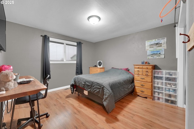 bedroom featuring baseboards and light wood finished floors