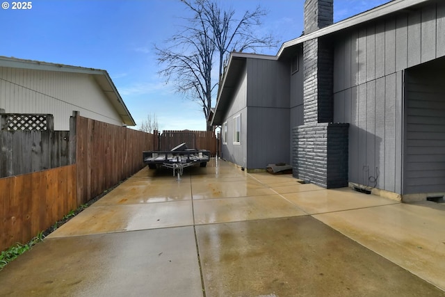 view of home's exterior featuring a patio area, a chimney, and fence