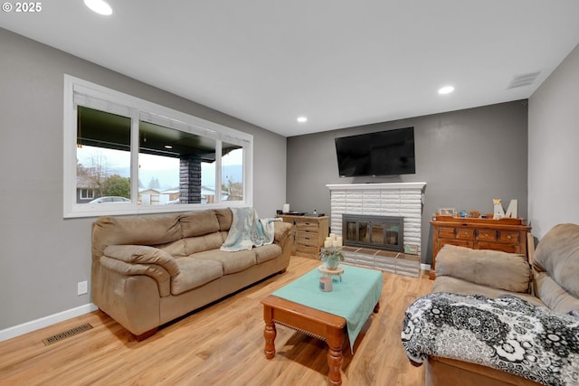 living area with visible vents, a fireplace, and wood finished floors