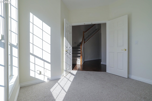 interior space featuring carpet floors, plenty of natural light, baseboards, and stairs