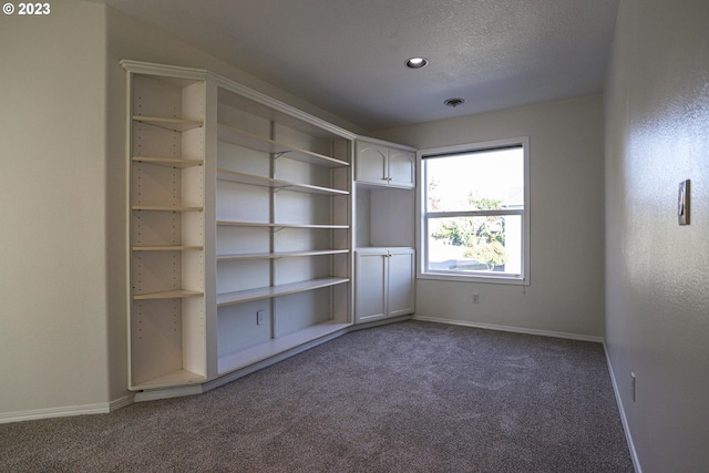 unfurnished bedroom with a textured ceiling, carpet flooring, visible vents, and baseboards