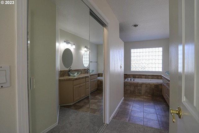 bathroom featuring a textured ceiling, tile patterned flooring, visible vents, vanity, and a bath