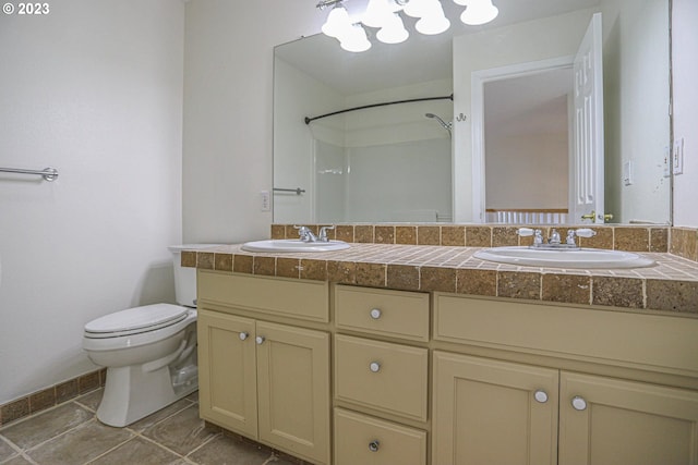 bathroom with toilet, tile patterned flooring, double vanity, and a sink