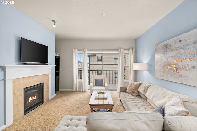 carpeted living area with a tile fireplace and baseboards