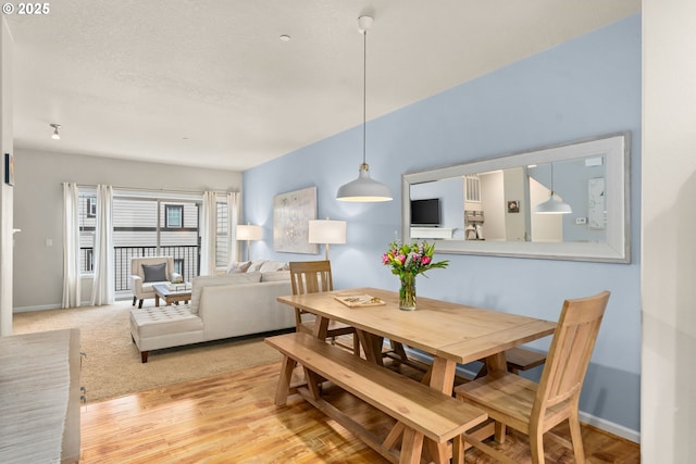 dining room featuring light wood-style floors, baseboards, and a textured ceiling