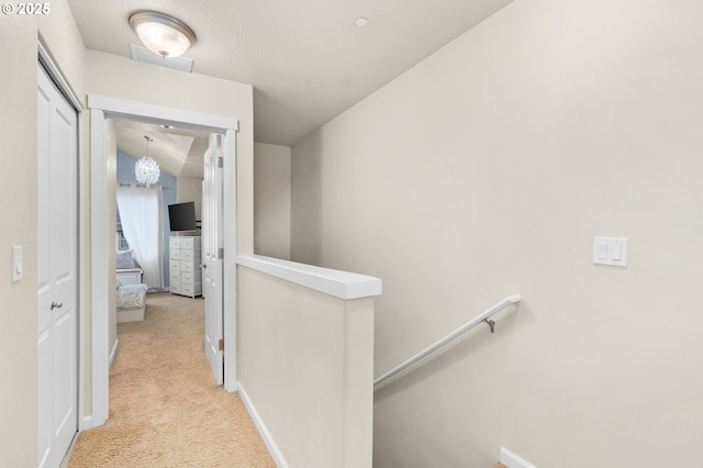 hall featuring carpet, baseboards, and an upstairs landing