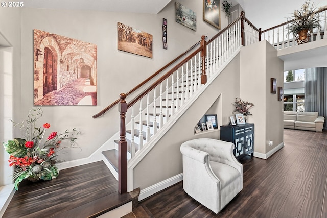 staircase featuring a towering ceiling and hardwood / wood-style floors