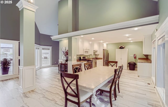 dining area with a towering ceiling, sink, and ornate columns