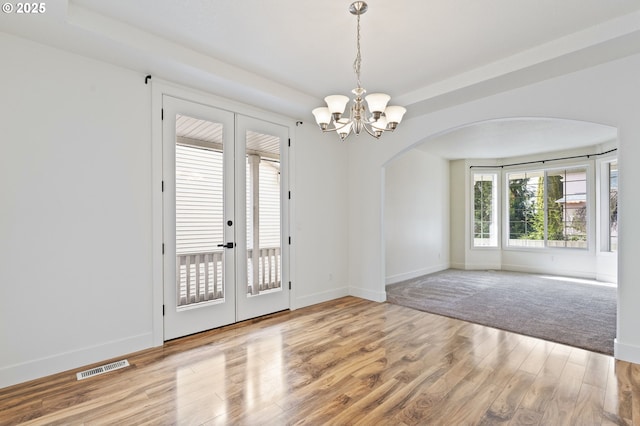 doorway with a notable chandelier, hardwood / wood-style flooring, and french doors