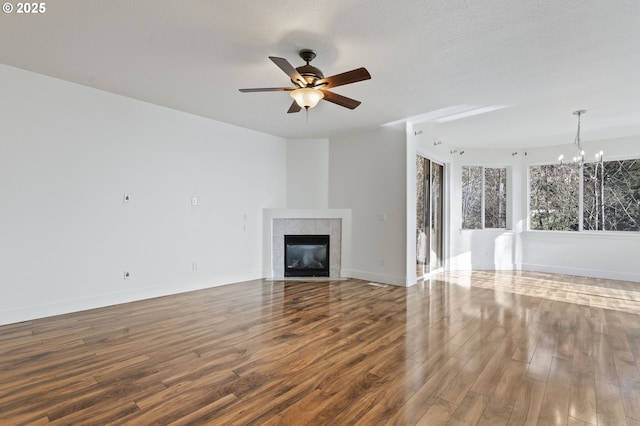 unfurnished living room featuring hardwood / wood-style floors, ceiling fan with notable chandelier, a fireplace, and a textured ceiling