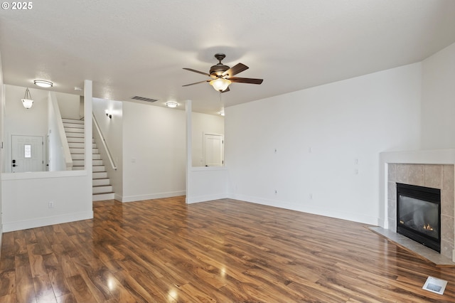 unfurnished living room featuring dark hardwood / wood-style flooring, a tile fireplace, and ceiling fan