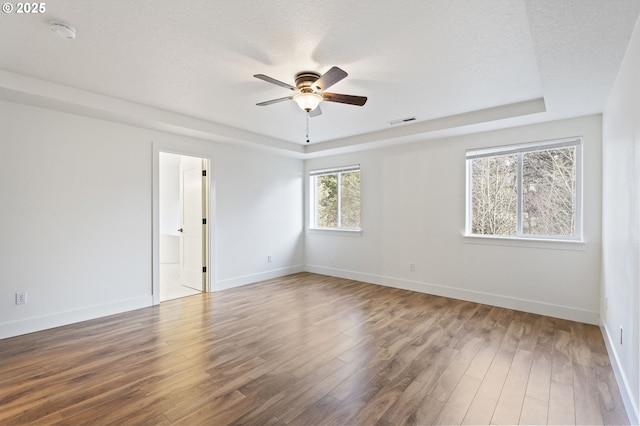 unfurnished room with a tray ceiling, a textured ceiling, wood-type flooring, and ceiling fan