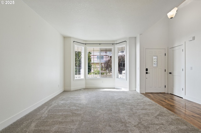 foyer entrance featuring a textured ceiling and dark colored carpet