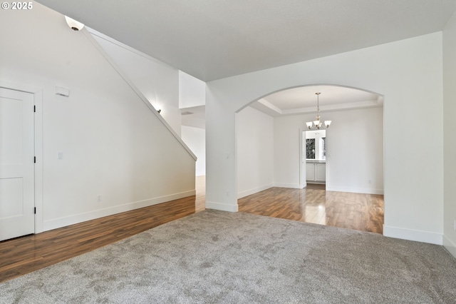 unfurnished living room featuring wood-type flooring, a raised ceiling, and a notable chandelier