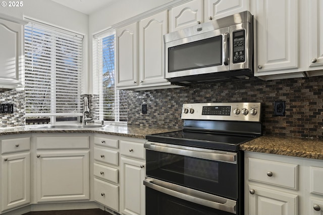 kitchen featuring tasteful backsplash, white cabinetry, sink, dark stone counters, and stainless steel appliances