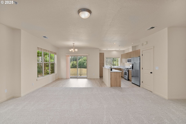 608 NE Adwick Dr, Beaverton, OR 97006 - kitchen with appliances with stainless steel finishes, open floor plan, a chandelier, light colored carpet, and light countertops