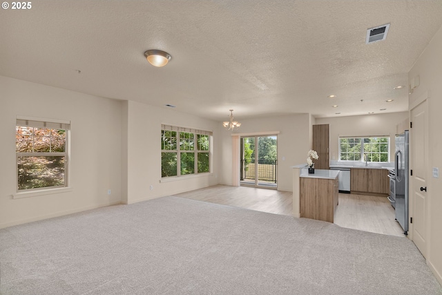 608 NE Adwick Dr, Beaverton, OR 97006 - unfurnished living room with light carpet, a chandelier, a textured ceiling, and recessed lighting