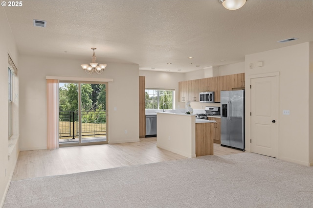 608 NE Adwick Dr, Beaverton, OR 97006 - kitchen with stainless steel appliances, light colored carpet, a kitchen island, a chandelier, and light countertops