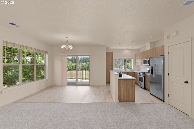 608 NE Adwick Dr, Beaverton, OR 97006 - kitchen with stainless steel appliances, light countertops, a chandelier, open floor plan, and a textured ceiling