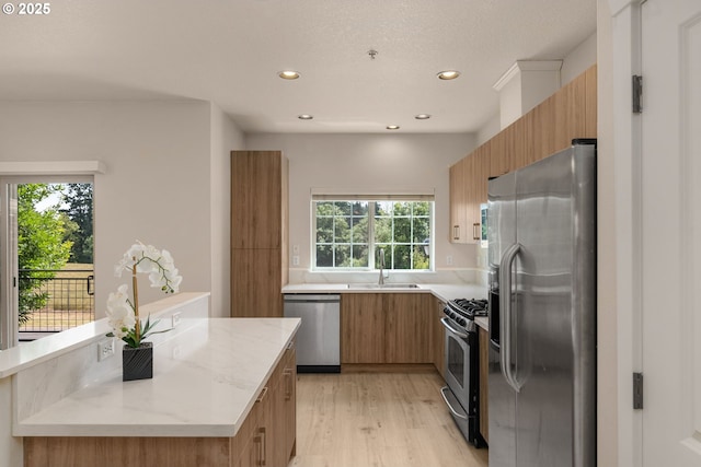 608 NE Adwick Dr, Beaverton, OR 97006 - kitchen featuring stainless steel appliances, modern cabinets, light wood-style flooring, brown cabinetry, and recessed lighting