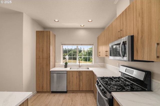 608 NE Adwick Dr, Beaverton, OR 97006 - kitchen with stainless steel appliances, light stone countertops, recessed lighting, light wood-style flooring, and brown cabinetry