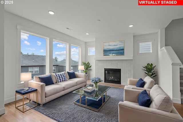 living area with a glass covered fireplace, recessed lighting, wood finished floors, and baseboards