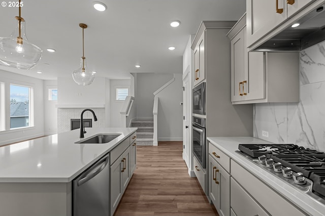 kitchen with under cabinet range hood, stainless steel appliances, gray cabinets, and a sink